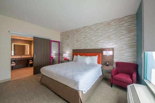 a hotel room with a bed and a red chair at Home2 Suites By Hilton Kingsland in Kingsland