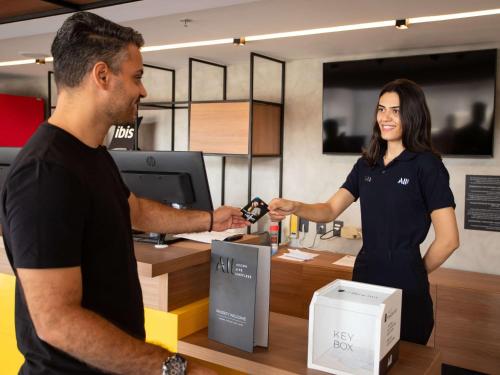 a man and a woman standing next to a cash register at Ibis Serra Talhada in Serra Talhada