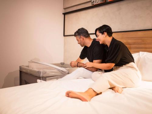 two men sitting on top of a bed at Ibis Serra Talhada in Serra Talhada