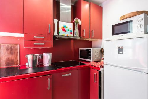 une cuisine rouge avec des armoires rouges et un réfrigérateur blanc dans l'établissement Horizon des Fleurs - Paris 15 mn des Champs Élysée, à Paris