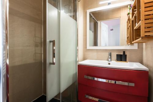 La salle de bains est pourvue d'un lavabo rouge et d'un miroir. dans l'établissement Horizon des Fleurs - Paris 15 mn des Champs Élysée, à Paris