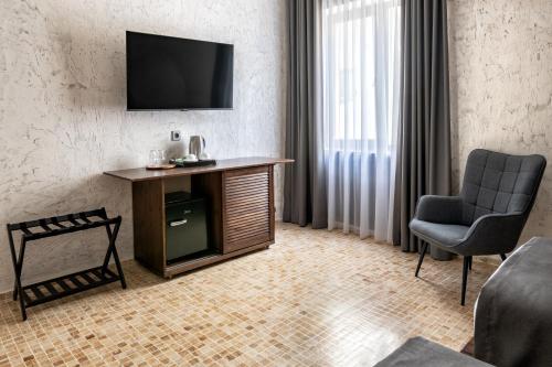 a living room with a tv on a wall with a chair at Kazma Boutique Hotel in Tbilisi City