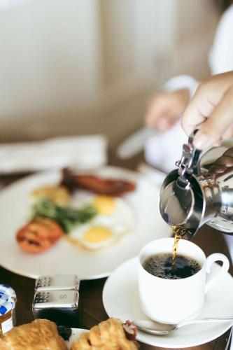 een persoon giet koffie in een kopje op een tafel bij World Class Hotel - Istanbul Airport in Arnavutköy