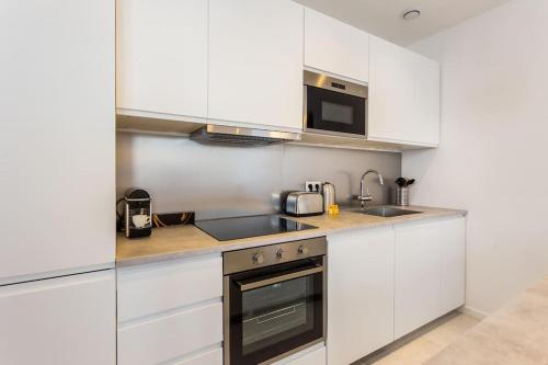 une cuisine avec des armoires blanches, un évier et une cuisinière dans l'établissement Appartement10P#Full Equipped#BONNE NOUVELLE#BOURSE, à Paris