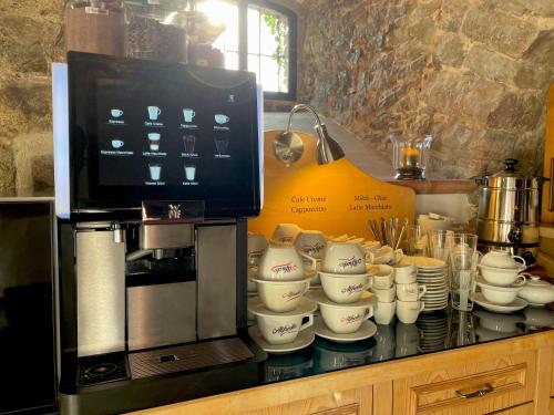 a counter with cups and plates next to a coffee maker at Hotel Grüner Baum in Würzburg