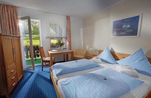 a hotel room with two beds and a table and a desk at Tommes Gästehaus Zur Mühle in Schmallenberg