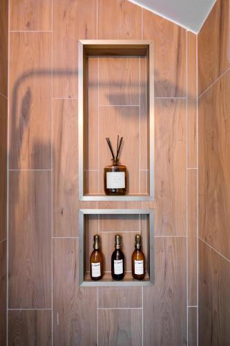 une étagère dans une salle de bains avec trois bouteilles de whisky dans l'établissement Jacuzzi Sauna privatif - La Cabanette Spa, à Saint-Maur-des-Fossés