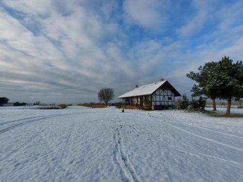 a barn in a field with snow on the ground at Svenceles 25 sodyba Namas su pirtimi ir krantine in Svenele