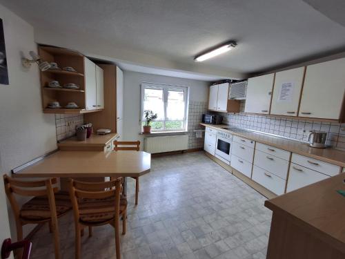 a kitchen with white cabinets and a table and chairs at Gästehaus Bavaria in Marktheidenfeld