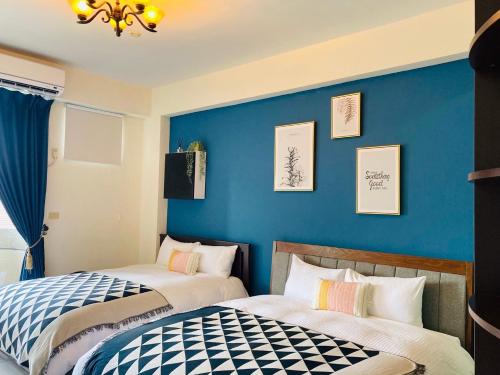 two beds in a room with a blue wall at Grace Homestay in Yujing