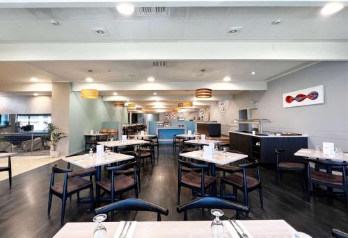 a dining room with tables and chairs in a restaurant at Sudima Hotel Lake Rotorua in Rotorua