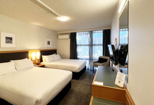 a hotel room with two beds and a television at Sudima Hotel Lake Rotorua in Rotorua
