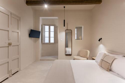 a white bedroom with a bed and a chair at 3 Cities Harbour Townhouse - near Valletta Ferry in Cospicua