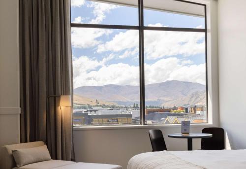 Habitación con ventana grande, cama y mesa. en Sudima Queenstown Five Mile, en Queenstown