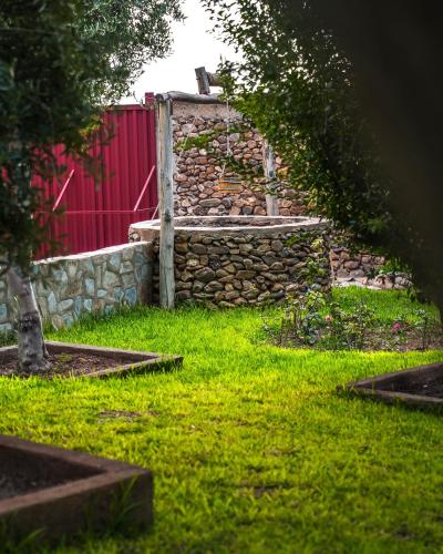 a garden with a stone wall and a red fence at Sakia Talamanzou in Talamennzou