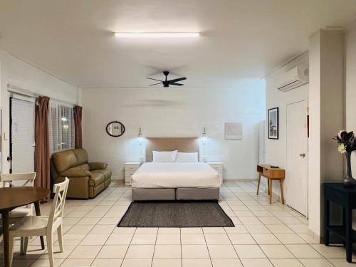 a bedroom with a bed and a couch and a table at Coffs Windmill Motel in Coffs Harbour