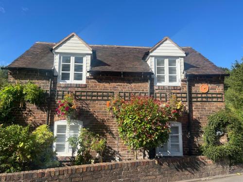 a red brick house with white windows and plants at Riverside Cottage in Ironbridge