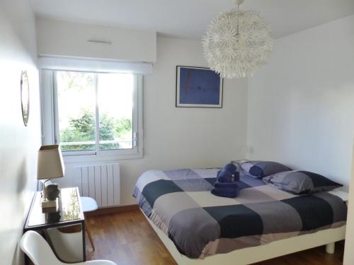 une chambre avec un lit et un lustre dans l'établissement La Fontaine,T2 au calme , parking, vue Erdre, à Nantes