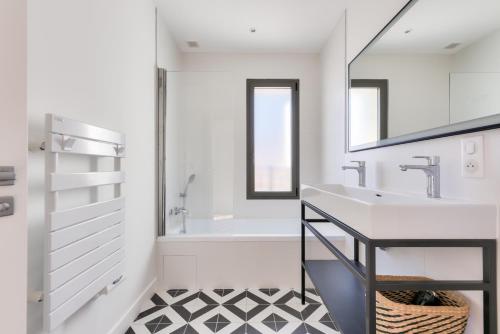 La salle de bains blanche est pourvue d'un lavabo et d'une baignoire. dans l'établissement Spacieuse Villa sous les pins & piscine, à Andernos-les-Bains