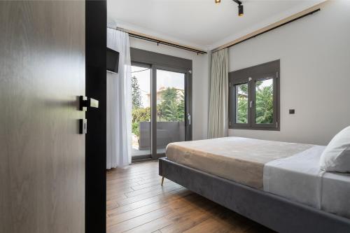 a bedroom with a bed and sliding glass doors at Noir Residence - Chic 2Br House Near Maleme Beach in Maleme