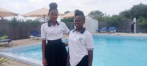 two girls are standing next to a swimming pool at Butah Gardens Watamu in Gede
