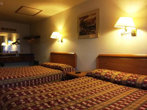 a hotel room with two beds and lamps on the wall at Milwaukie Inn Portland South in Milwaukie