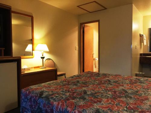 a hotel room with a bed and a desk and a mirror at Milwaukie Inn Portland South in Milwaukie