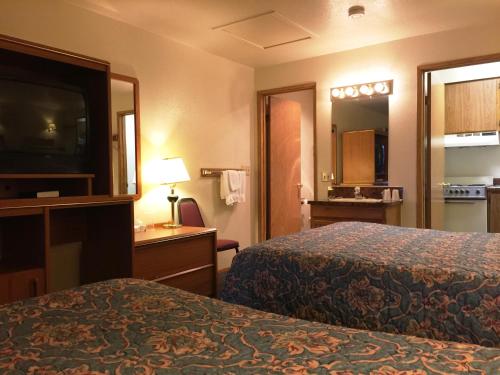 a hotel room with two beds and a flat screen tv at Milwaukie Inn Portland South in Milwaukie
