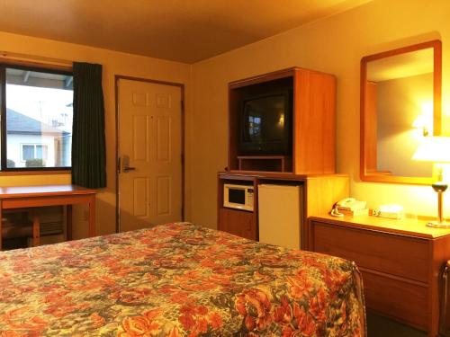 a bedroom with a bed and a mirror and a television at Milwaukie Inn Portland South in Milwaukie