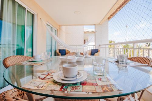 szklany stół z talerzami i kubkami na balkonie w obiekcie Golf Ville Resort Brisa do Golf -Apartamentos e Cobertura w mieście Aquiraz