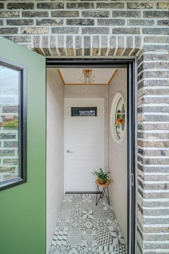 a hallway with a white door and a brick wall at Dongparang hanok stay in Gyeongju