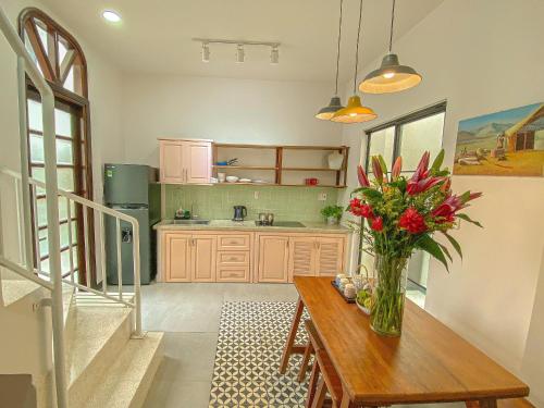 a kitchen with a wooden table with a vase of flowers at DƯỚI TÁN CÂY homestay in Tây Ninh