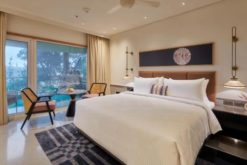 a bedroom with a large white bed and a table at The Dukes Retreat Khandala in Lonavala