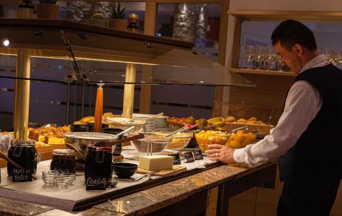 a man standing in a kitchen preparing food at Hotel Bel Sit in Comano Terme