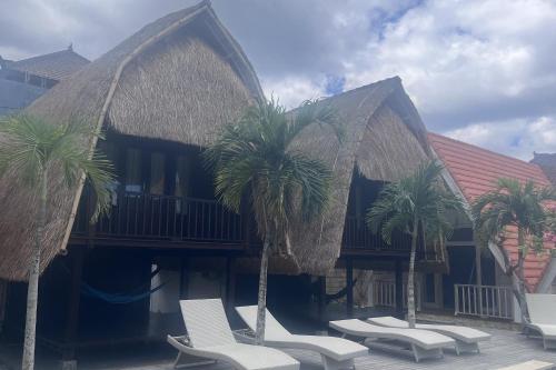 a group of chairs and palm trees in front of a building at Rama Garden Lembongan in Nusa Lembongan