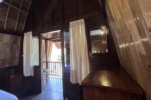 a room with a bed and a door with a window at Rama Garden Lembongan in Nusa Lembongan
