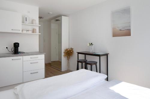 a white bedroom with a bed and a table at Ferienwohnung Romeo, sehr zentral in Freiburg im Breisgau