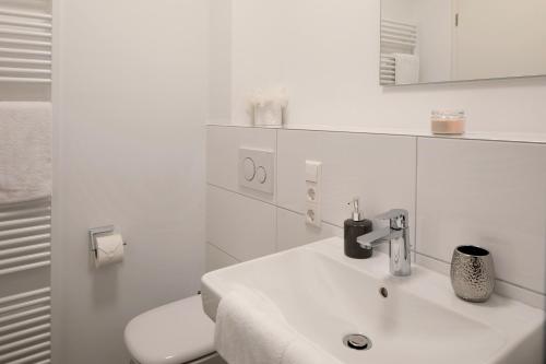 a white bathroom with a sink and a toilet at Ferienwohnung Romeo, sehr zentral in Freiburg im Breisgau