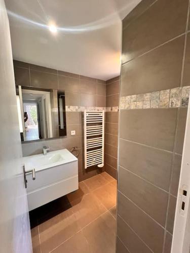 une salle de bain avec un lavabo blanc et un miroir dans l'établissement Logement Mésange600m à pied de SantaGiulia Jacuzzi, à Porto-Vecchio