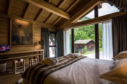 une chambre avec un grand lit et une grande fenêtre dans l'établissement Chalet grandiose au pied des pistes de Morzine - Vue imprenable, à Morzine