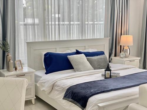 a white bedroom with a large bed with blue pillows at White Tara Villa in Chiang Mai