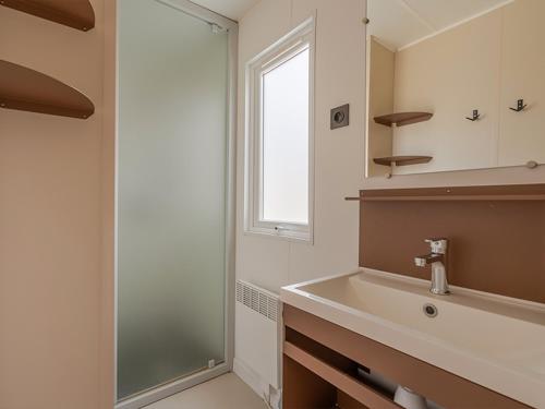 a bathroom with a sink and a glass shower at Camping Les Grenettes in Sainte-Marie-de-Ré