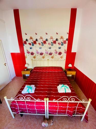 a bedroom with a red bed with flowers on the wall at Casa Fronte Mare in Marina di Mancaversa