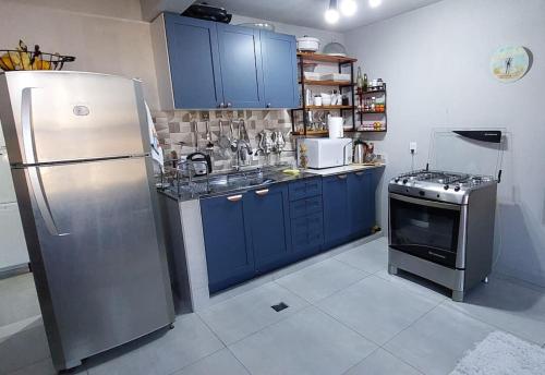 a kitchen with blue cabinets and a stainless steel refrigerator at Loft espaçoso e confortável in Três Marias