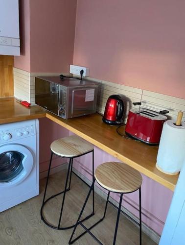 une cuisine avec un comptoir avec deux tabourets et un four micro-ondes dans l'établissement Jennifer, à Saint-Dizier