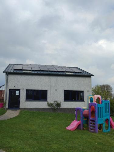 a building with a house with a playground in the grass at Bastogne Maison de vacances avec sauna in Bertogne