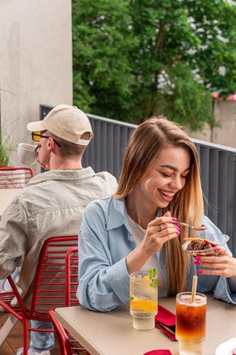 a woman sitting at a table eating a plate of food at LEV Lifestyle Hotel - Maestro in Lviv