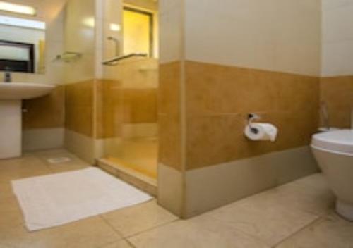 a bathroom with a shower and a toilet and a sink at Eseriani The Hotel in Naivasha