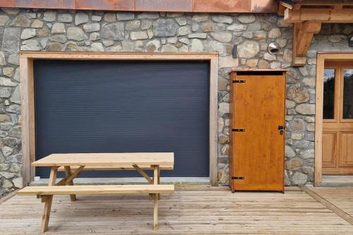 un banc en bois assis devant un garage dans l'établissement Appartement montagne 50m2 2 chambres et un canapé lit, aux Gets