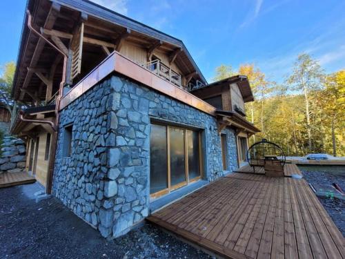 une maison avec une terrasse en bois devant elle dans l'établissement Appartement montagne 50m2 2 chambres et un canapé lit, aux Gets